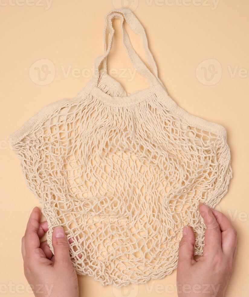 Empty reusable cotton mesh bag in female hands photo