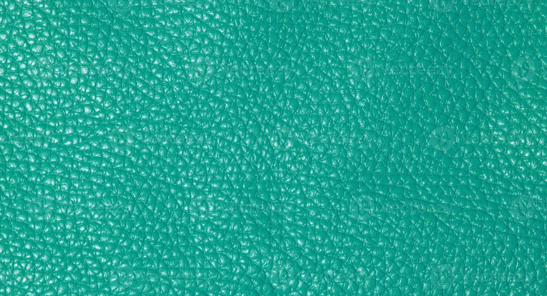 A close up full frame view of a vibrant teal colored leather texture, showcasing its natural grain photo