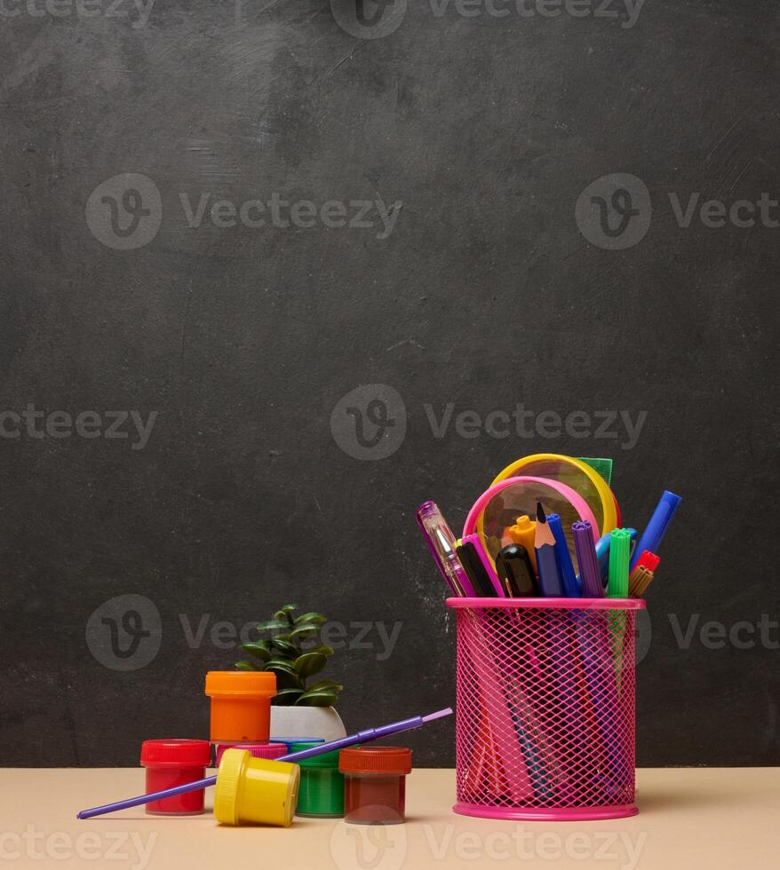 Colored pencils and watercolor paints on chalk board background, back to school photo
