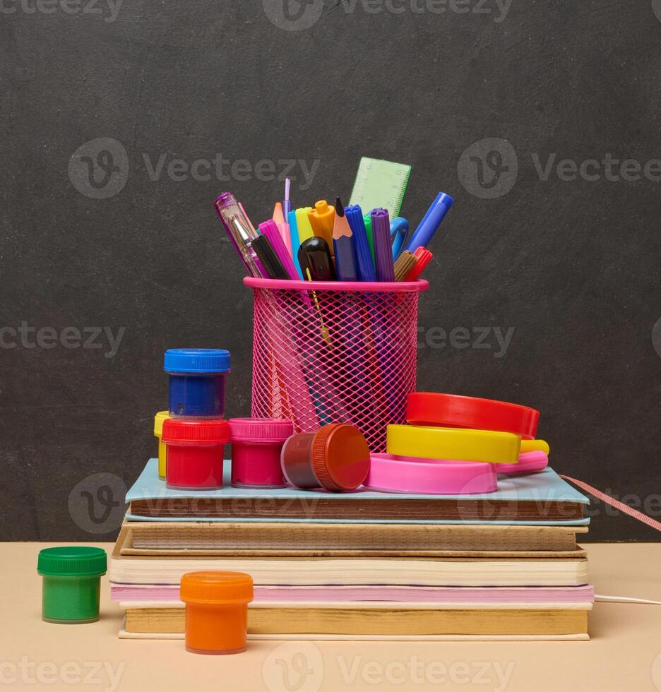 Colorful books, a pink glass with pens and pencils, and two magnifying glasses symbolizing learning, knowledge photo