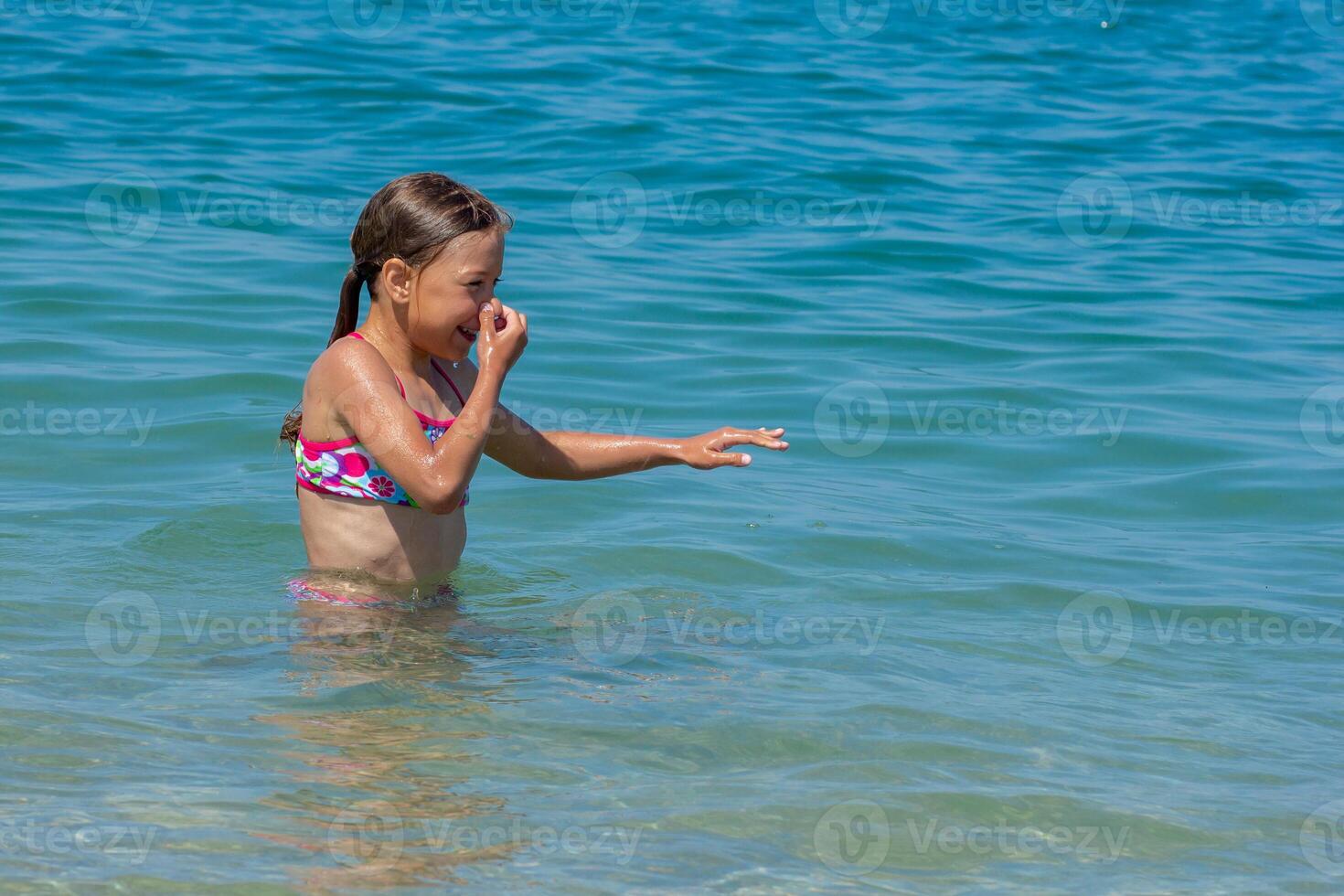 Caucasian happy and smiling child of 8 9 years closed her nose before diving and swimming in blue sea photo