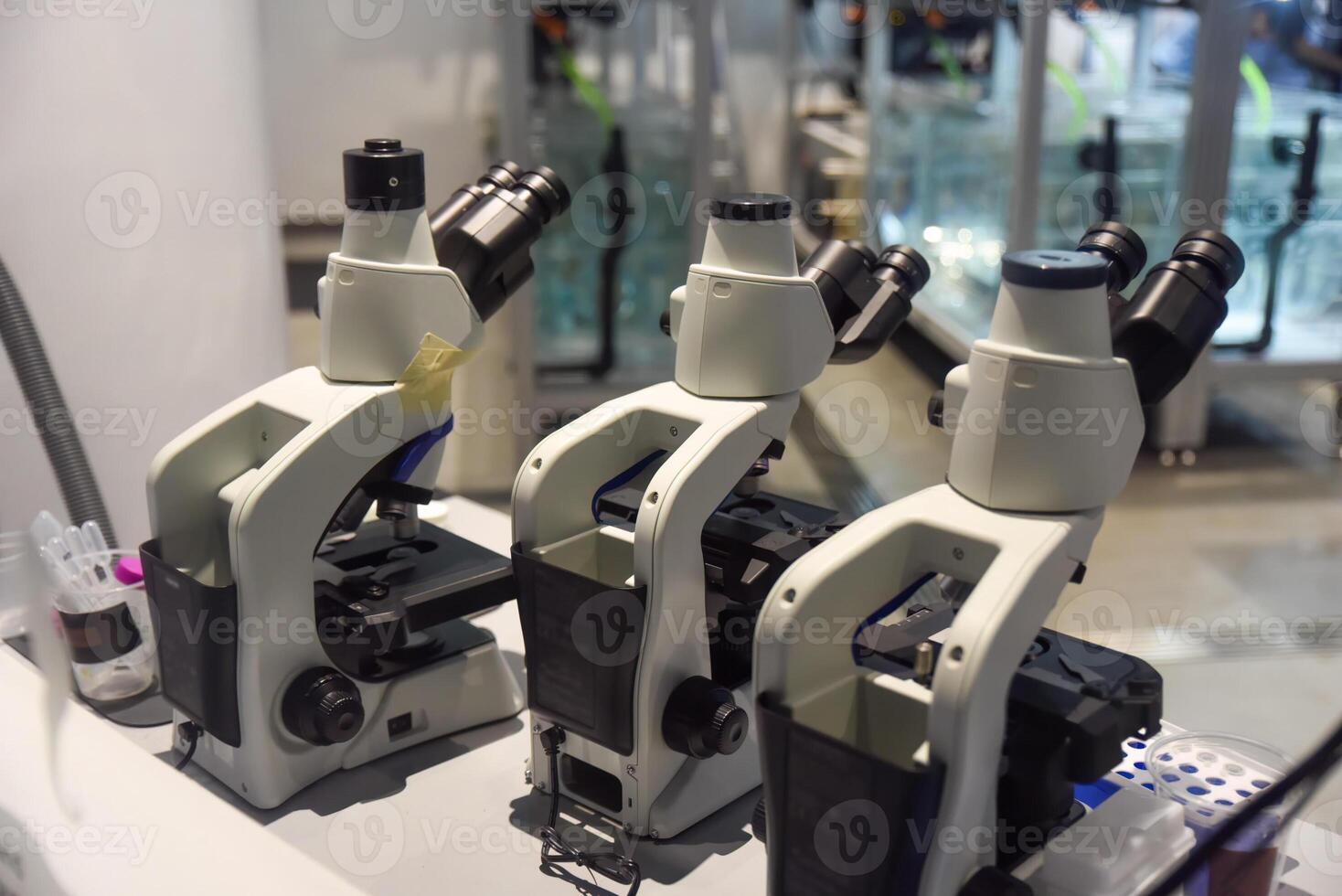 Three modern microscopes in a bright laboratory setting in Singapore, showcasing scientific research and technological precision. photo