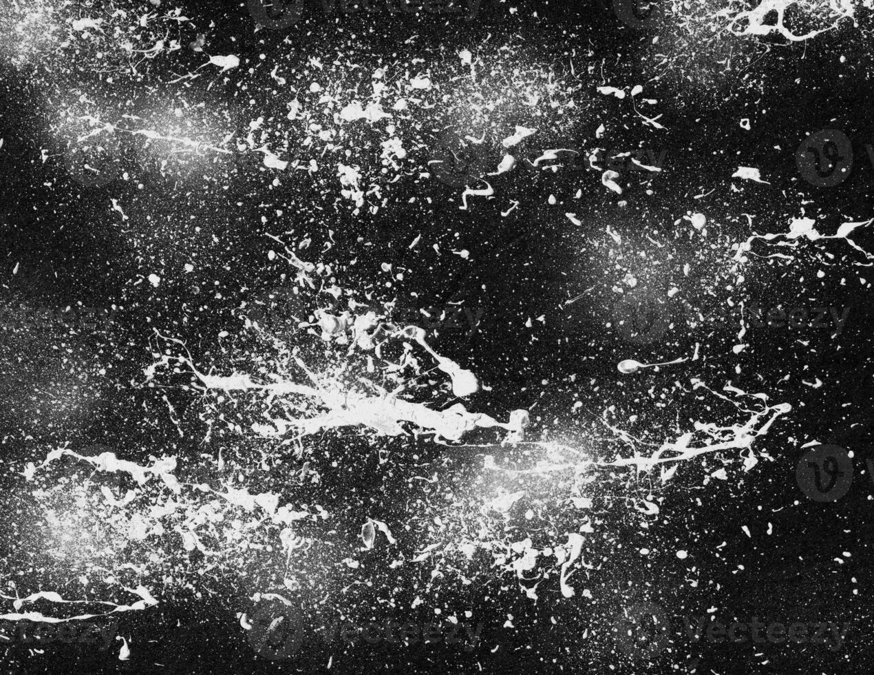 White paint splatter on black background. Abstract grunge paint spray texture. Suitable for overlay template. photo