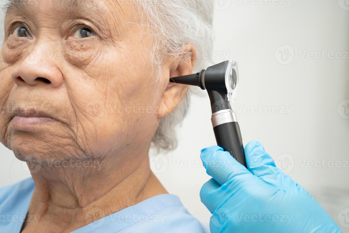 Otolaryngologist or ENT physician doctor examining patient ear photo
