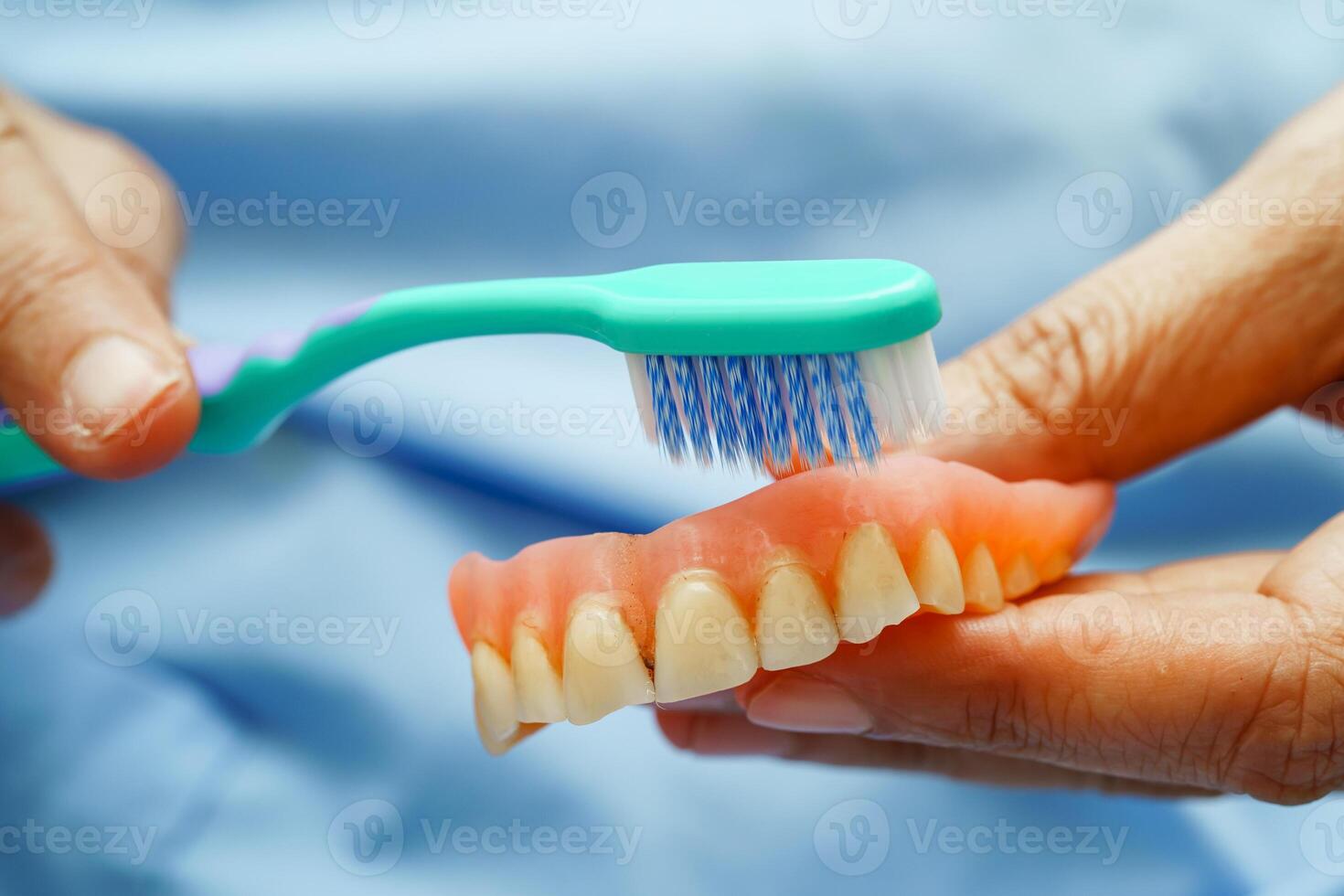 Asian senior woman patient clean teeth denture with toothbrush for chew photo