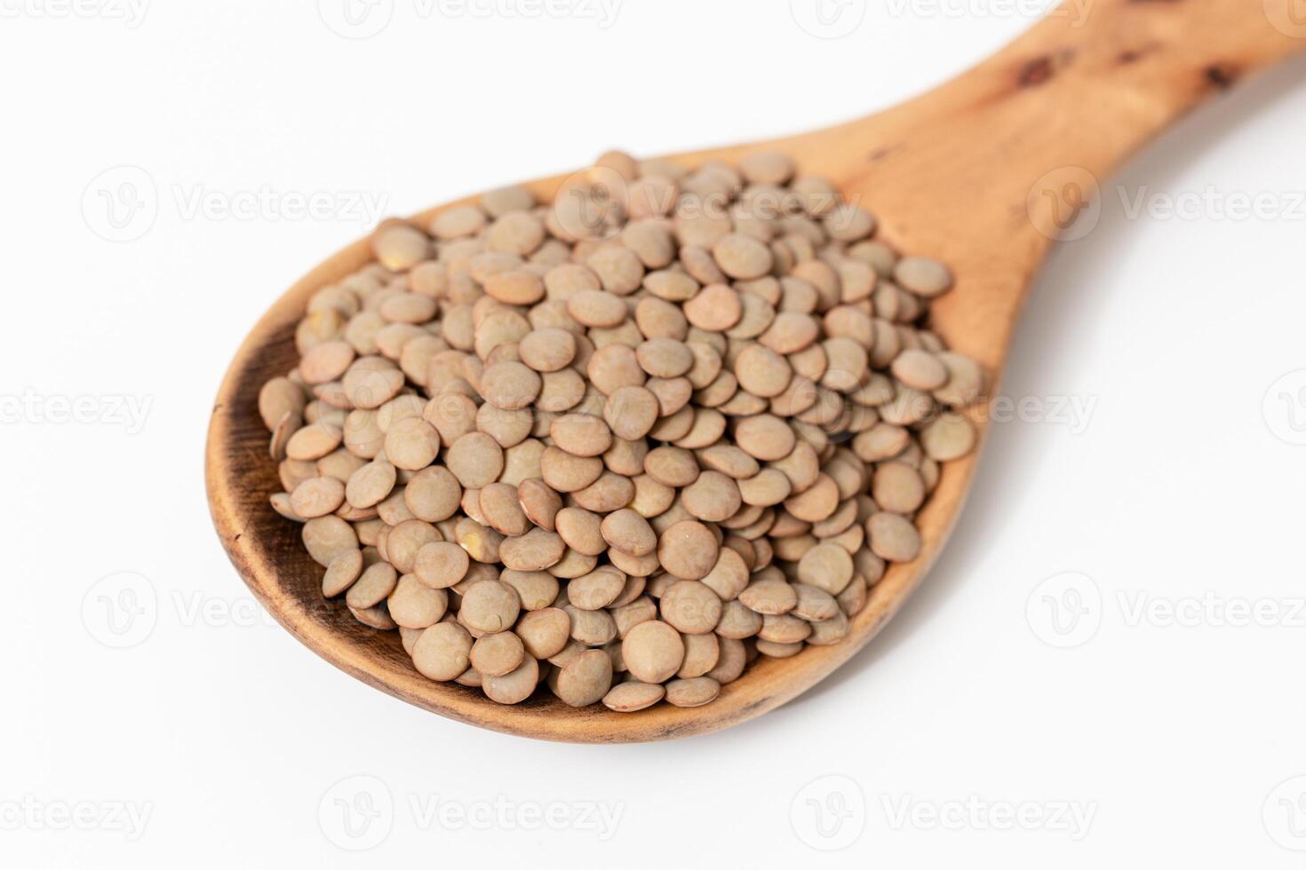 Close-up of a wooden spoon with brown lentils isolated on white background photo