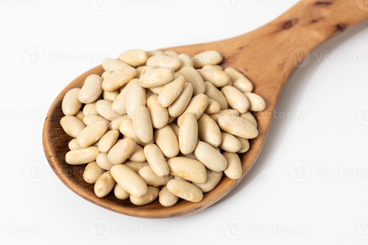 Close-up of a wooden spoon with raw cannellini beans isolated on white background photo