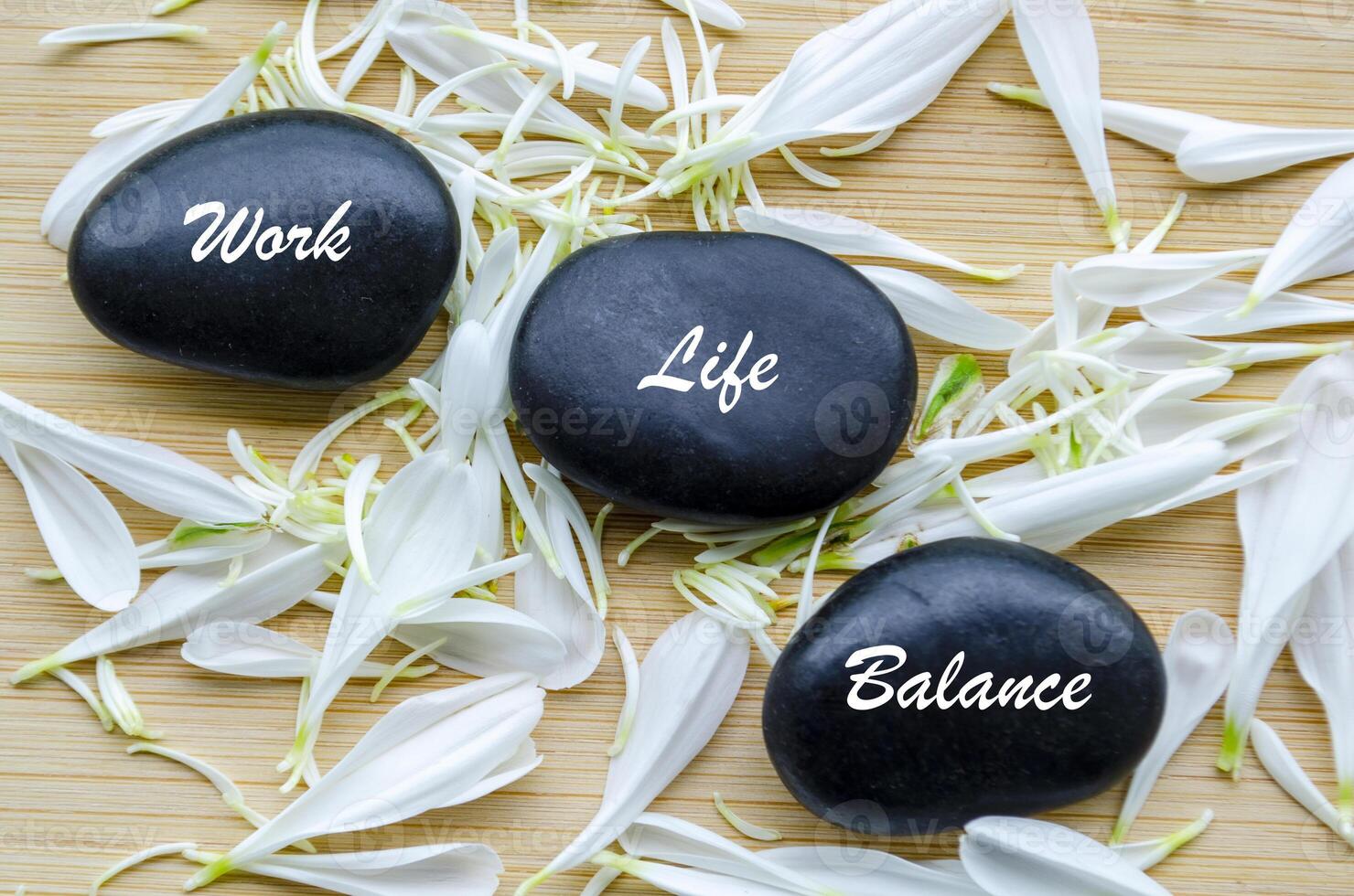 Top view of Work Life Balance text on zen stones with white color flower petals photo