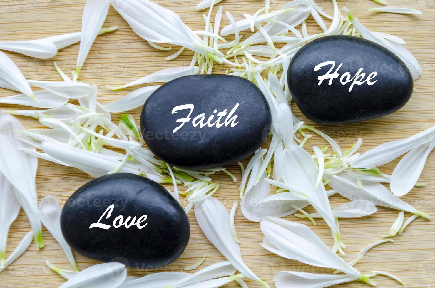Top view of Hope, Faith and Love text on zen stones with white color flower petals photo