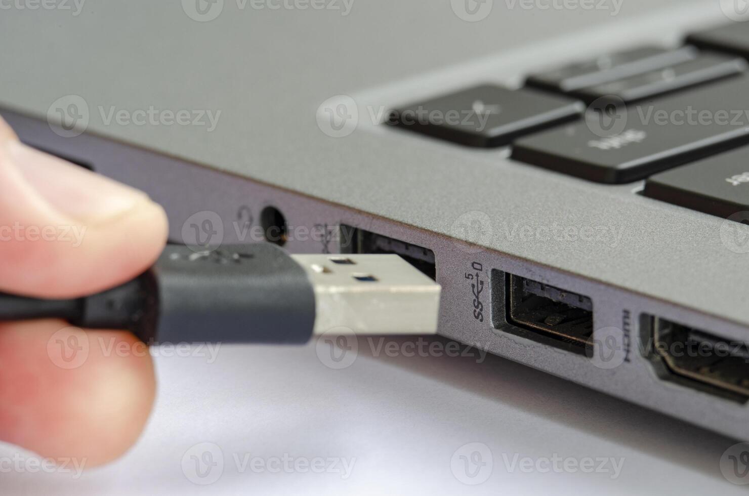 USB being plugged into laptop highlighting risk of unauthorized data transfer or malware photo