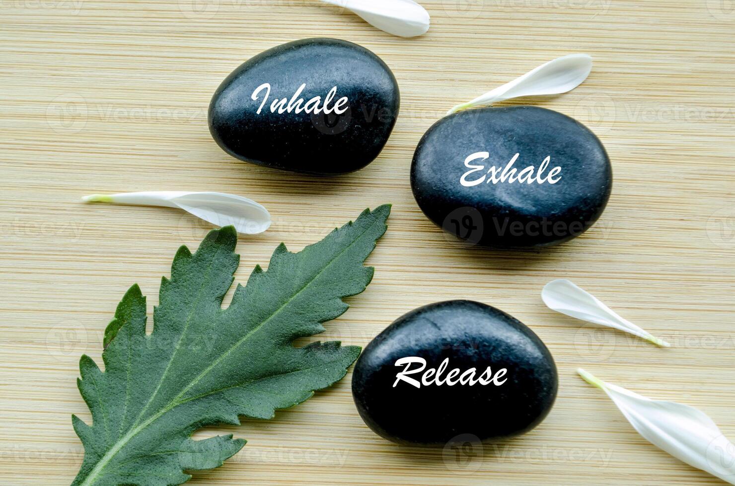 Inhale, Exhale and Release text on zen stones surrounded by flower petals. Inner peace concept photo