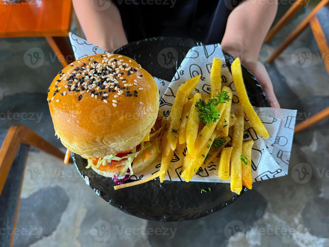 A person is holding,,, a plate with a burger and fries photo