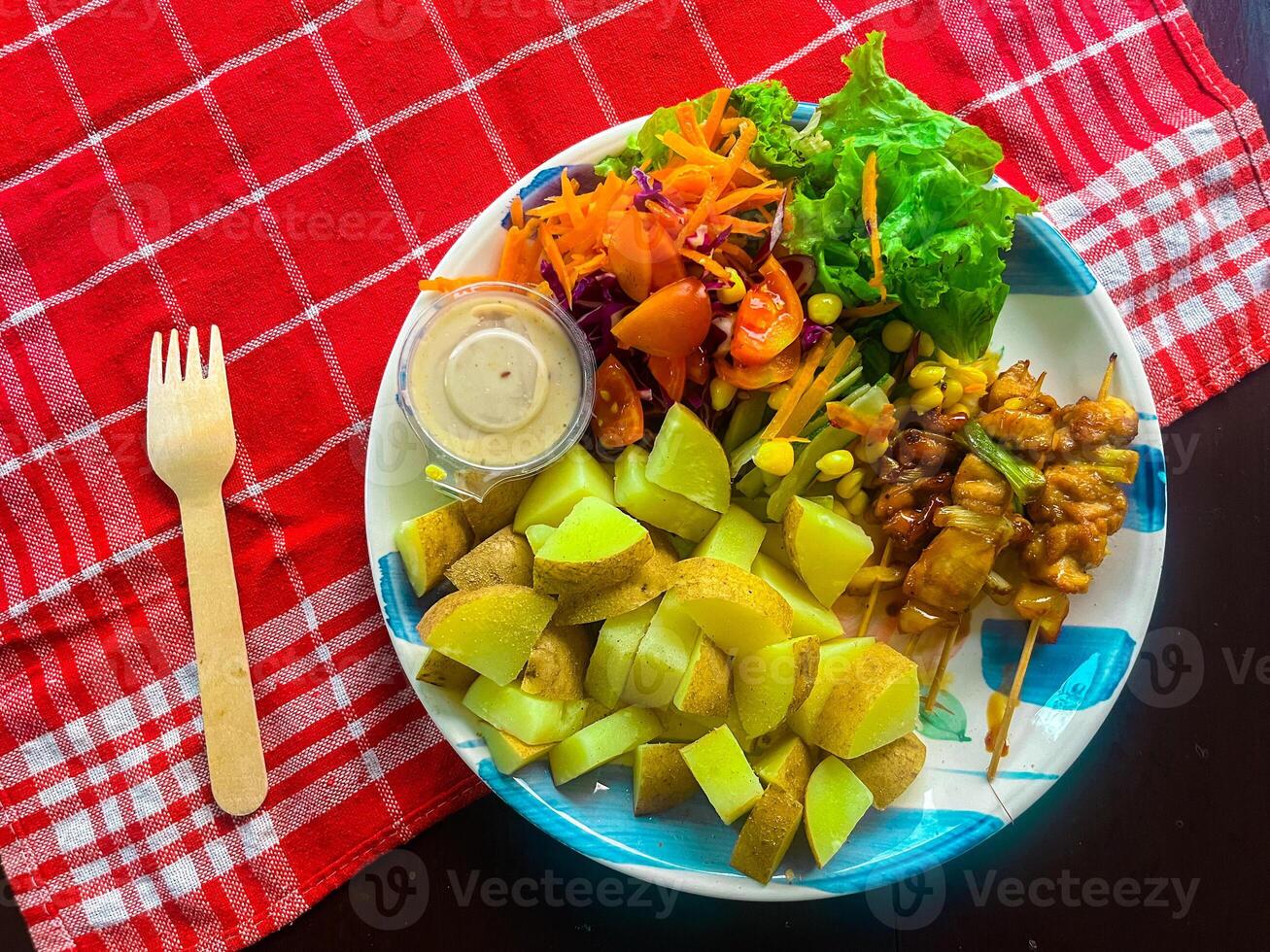 Fresh healthy, vegetable salad, of cheese, tomato, carrot, potato, green pepper and green basil leaves, top view A plate of food with a fork on it. photo
