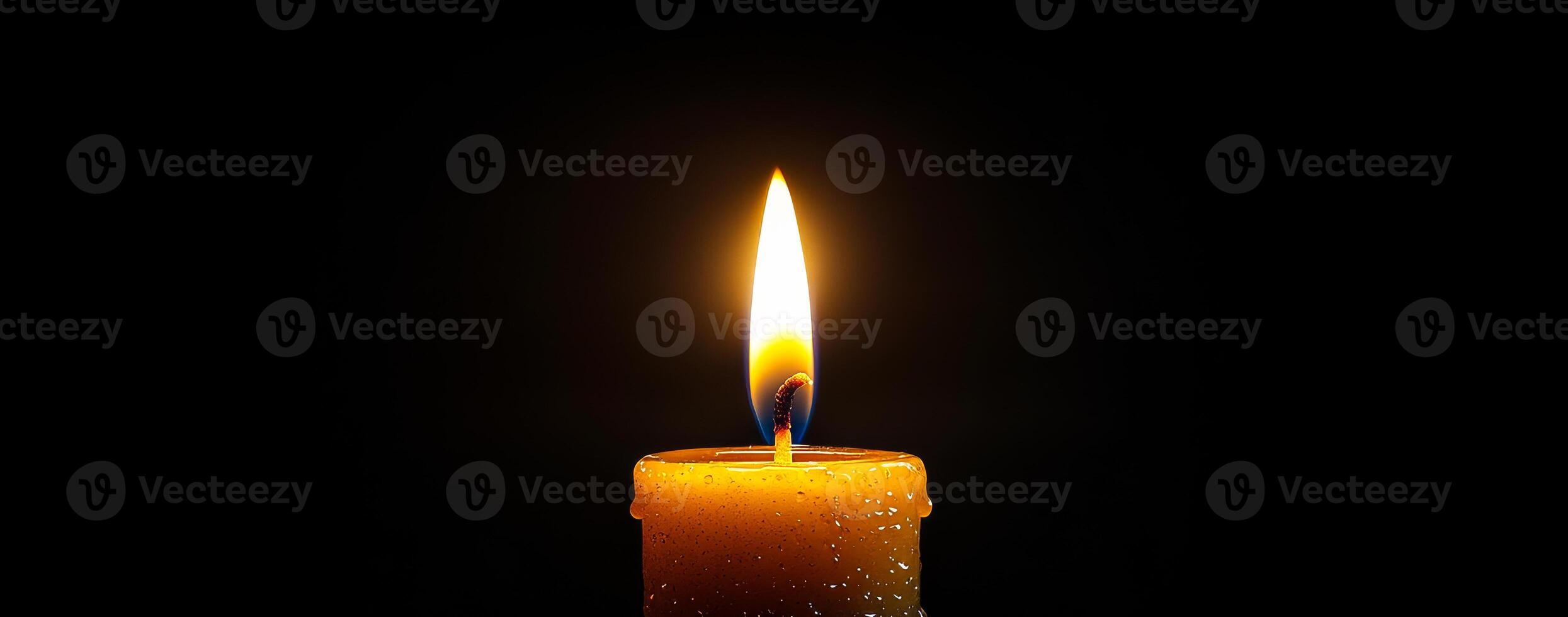 Candle flame glowing in dark environment. A single candle burns brightly in a dark space, casting warm light and creating a tranquil atmosphere. photo