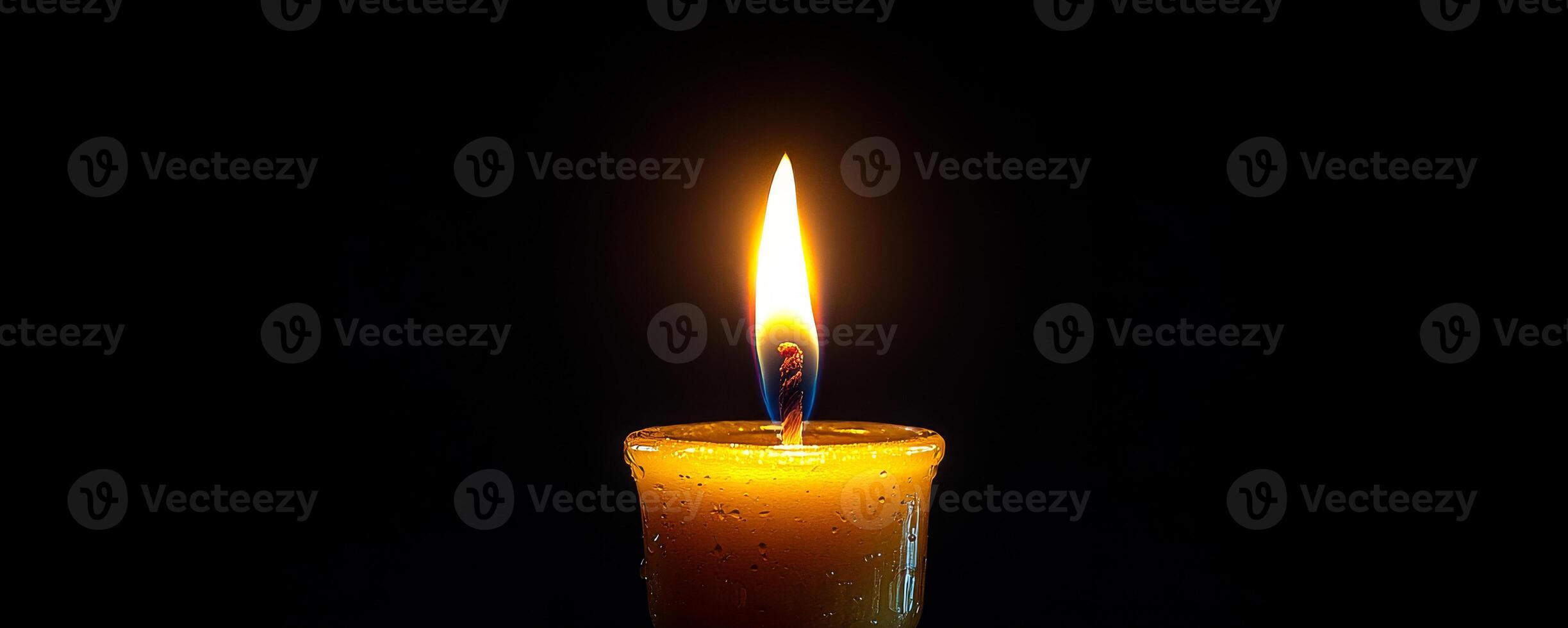 Candle flickering in dark background. A single candle burns brightly in a dark setting, creating a warm and serene atmosphere with its gentle glow. photo