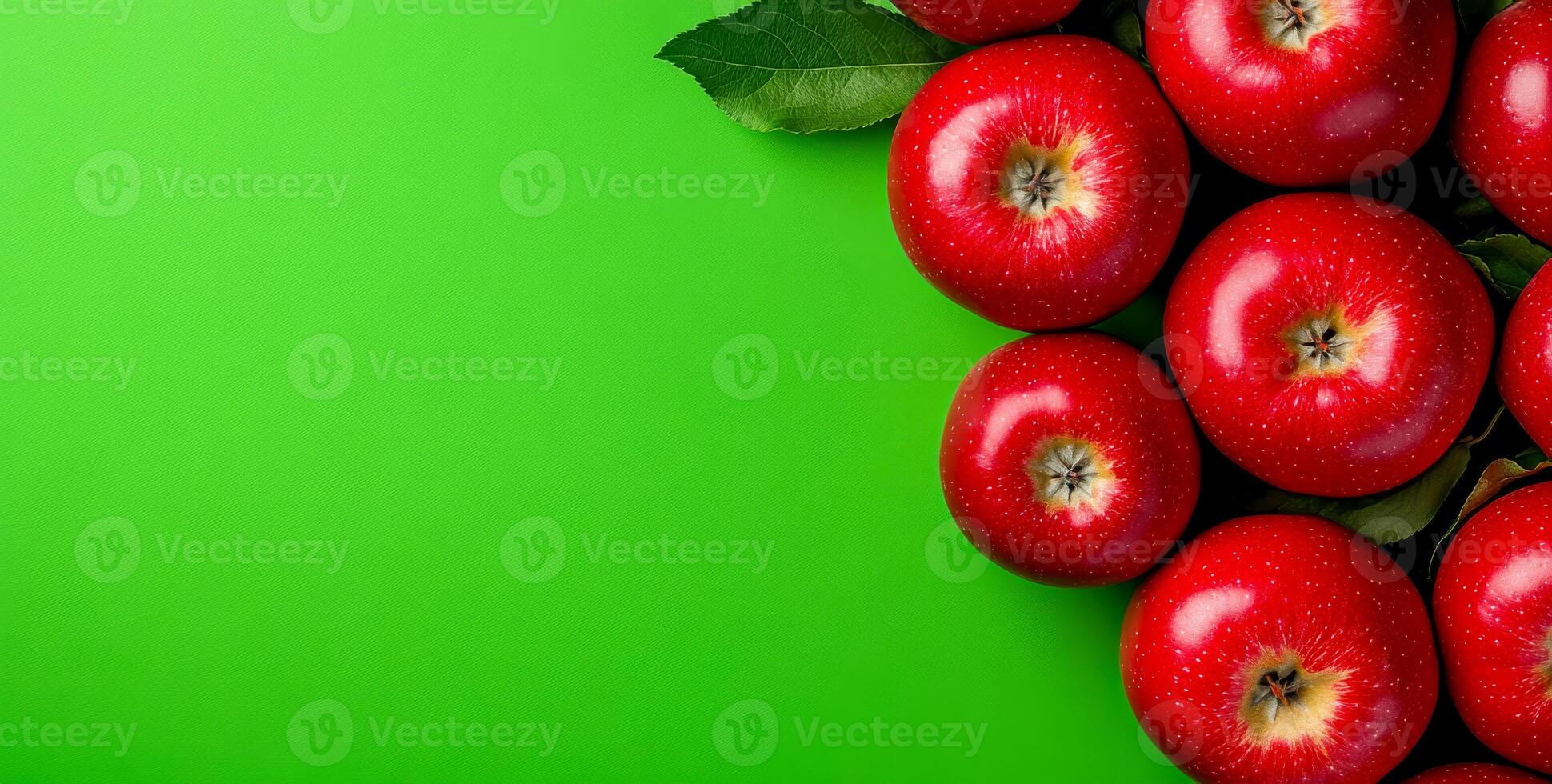 Red apples on green bg. Vibrant red apples arranged on a vivid green surface, showcasing their fresh and glossy appearance with leaves. photo