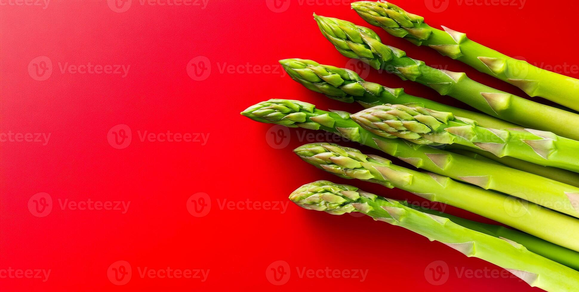 Green asparagus on red bg. Bright green asparagus stalks arranged neatly against a vibrant red backdrop, showcasing their fresh appearance. photo