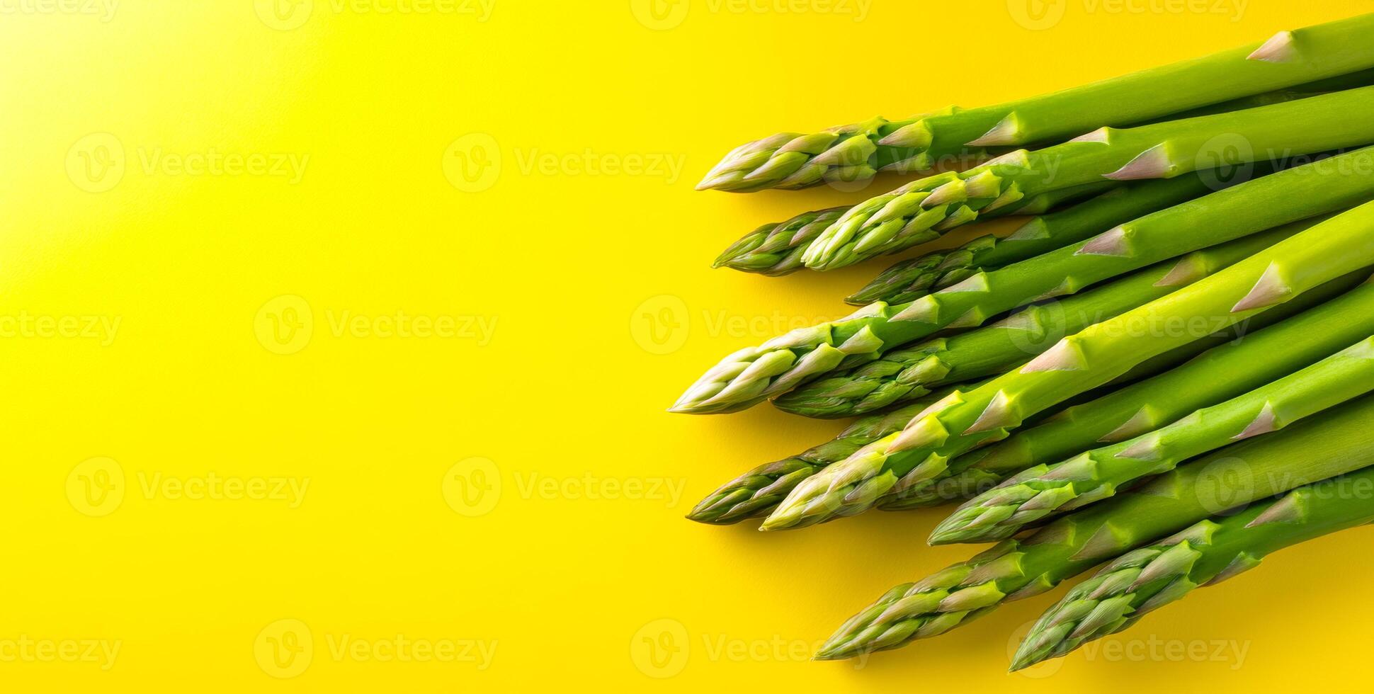 Green asparagus on yellow bg. Vibrant green asparagus spears arranged neatly against a bright yellow backdrop, showcasing their freshness and color. photo