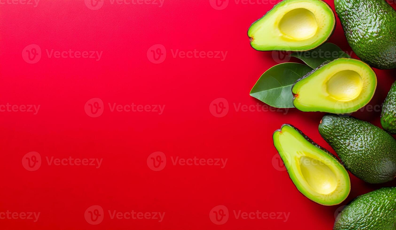 Fresh avocados arranged on a red surface. Halved avocados with green flesh placed next to whole avocados on a vibrant red backdrop, highlighting their texture. photo