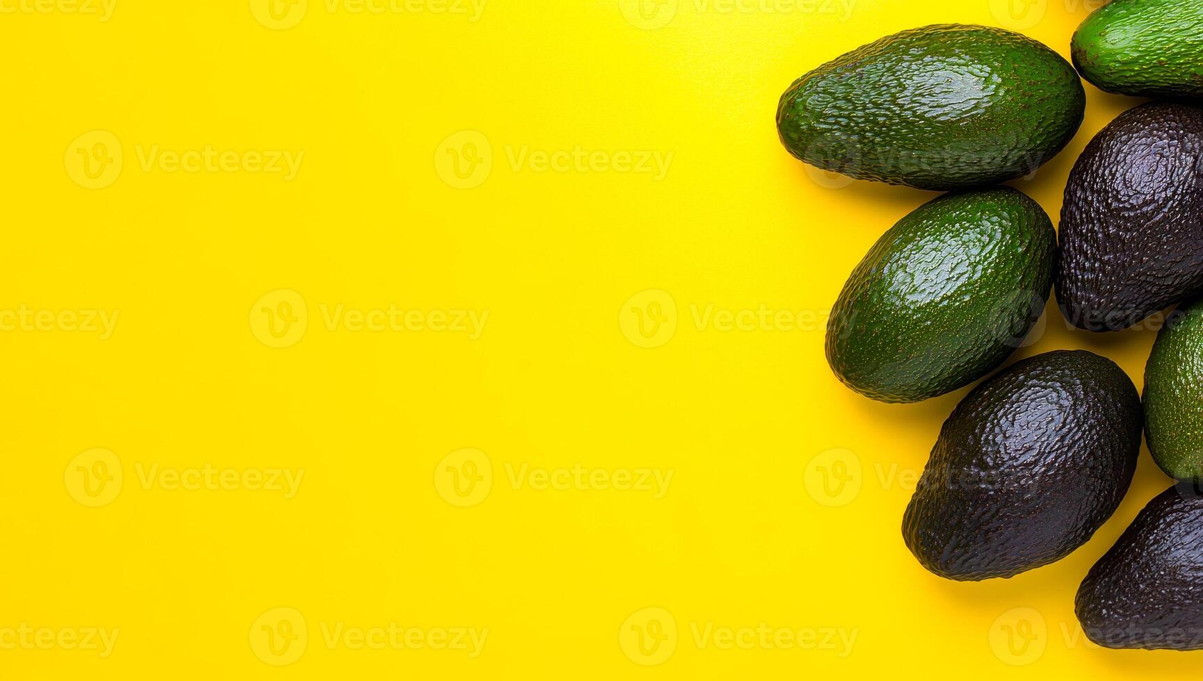 Avocados on yellow backdrop. A collection of ripe avocados arranged on a bright yellow surface, showcasing their rich colors and textures. photo