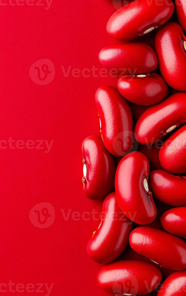 Red beans on bright backdrop. Red kidney beans are artfully placed against a bright red backdrop, showcasing their glossy surfaces and unique shapes. photo
