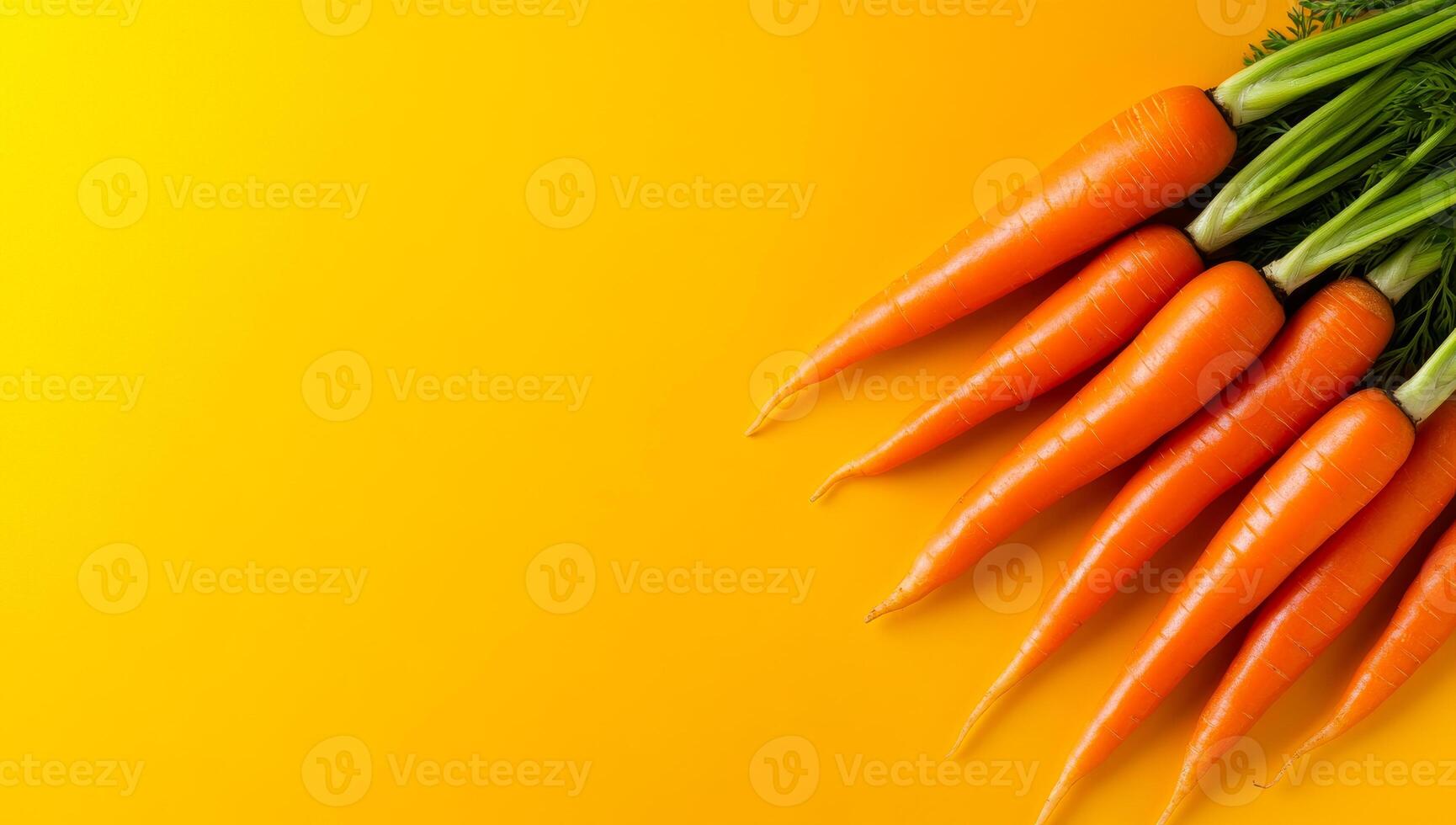 Carrots on yellow backdrop. Freshly harvested carrots with green tops lie in an appealing arrangement against a vibrant yellow backdrop. photo