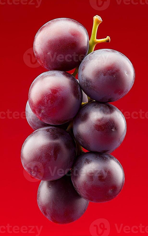 Fresh red grapes on a vibrant background. Bunch of plump red grapes displayed against a bold red backdrop, showcasing their rich color and natural texture. photo