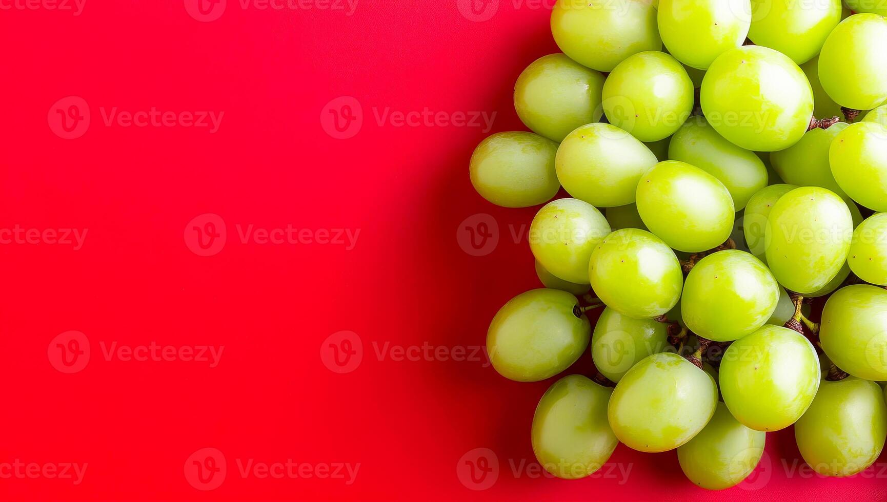 Vibrant green grapes background. A cluster of fresh green grapes resting against a bright red backdrop highlights their natural beauty and freshness. photo