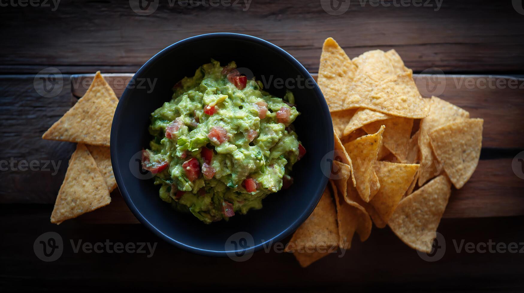 Guacamole in a bowl with tortilla chips on a wooden table photo