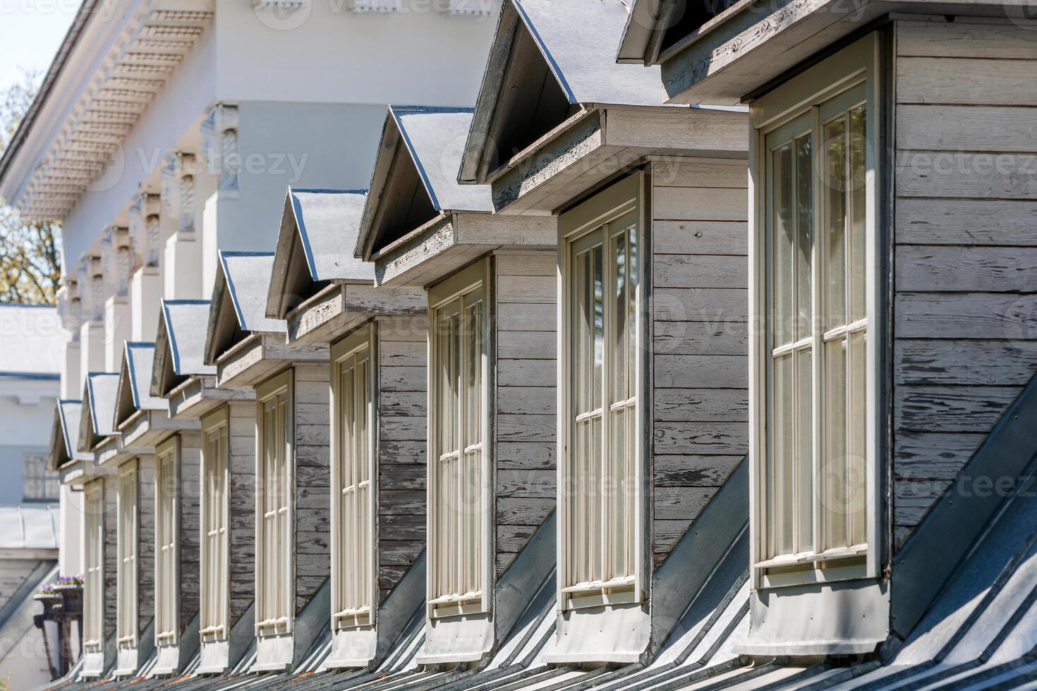 Dormer windows in a row on the pitched roof of a historic building, illuminated by the sun. photo