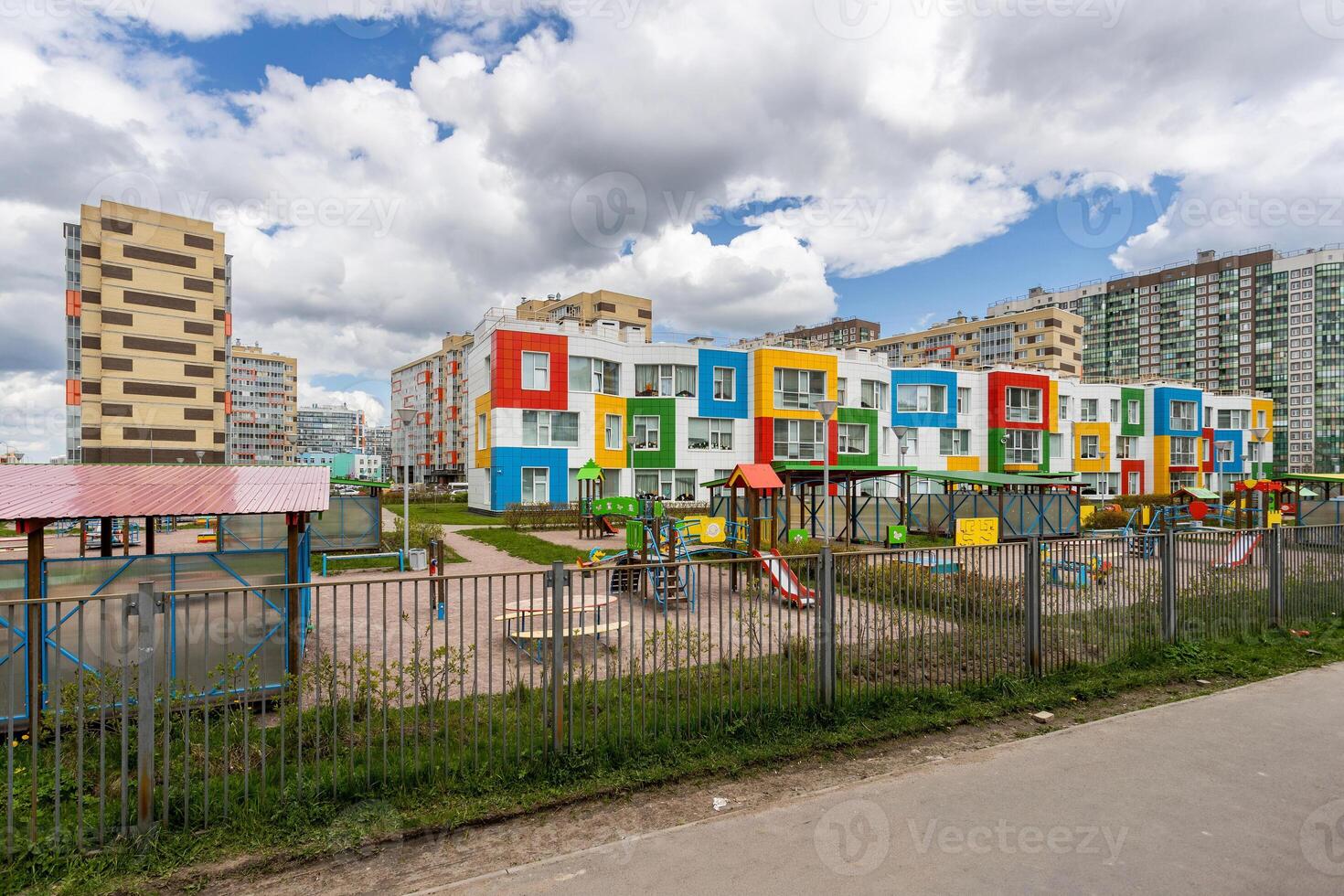 Bright kindergarten building with a multicolored facade and a playground against the background of modern residential buildings. photo