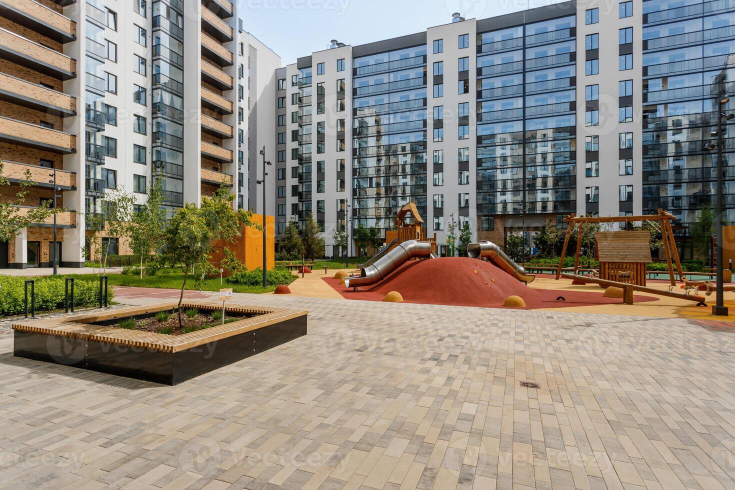 Modern playground with slides and swings in the courtyard of a new residential complex with panoramic windows. photo