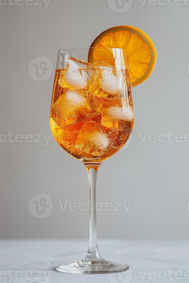 A glass of Aperol Spritz with ice and an orange slice on a thin stem, on a gray uniform background. photo