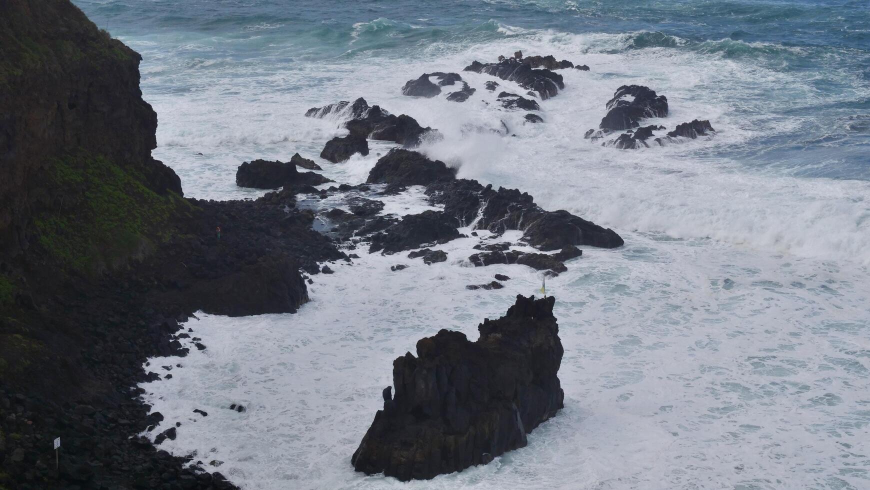 A view of the ocean from above with rocks and waves photo