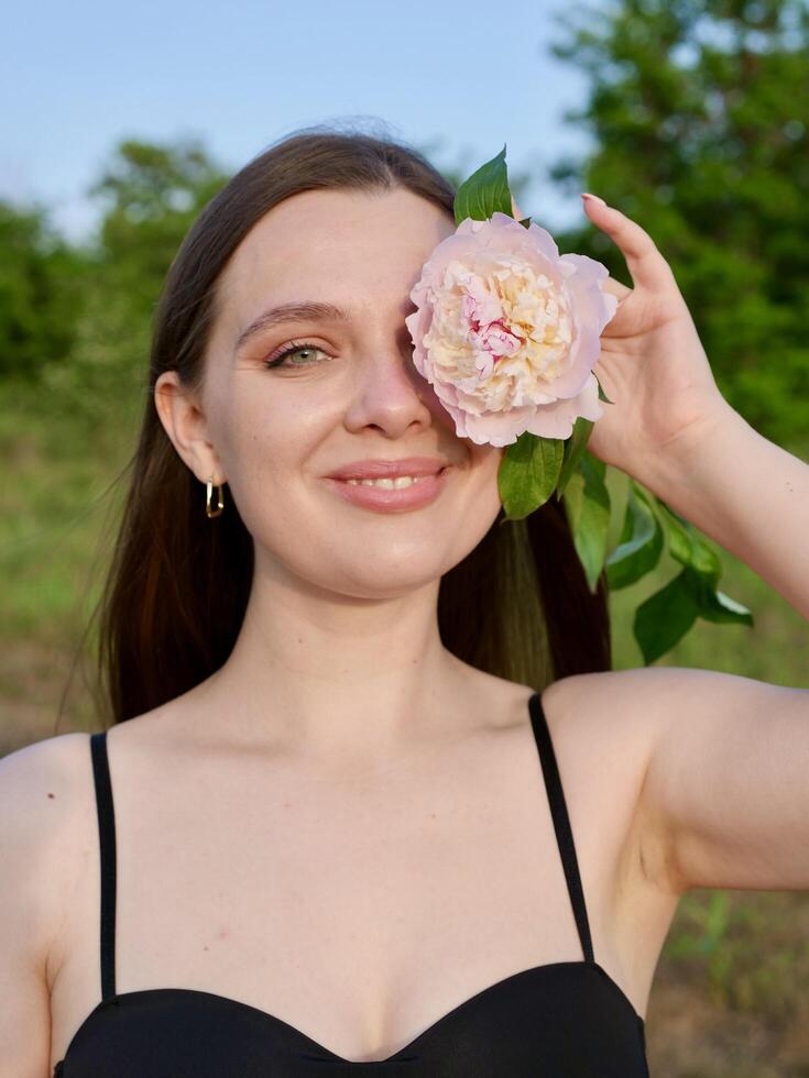 A woman in a black bra top is holding a flower photo