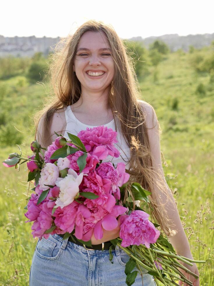 A girl is holding a bunch of pink flowers photo