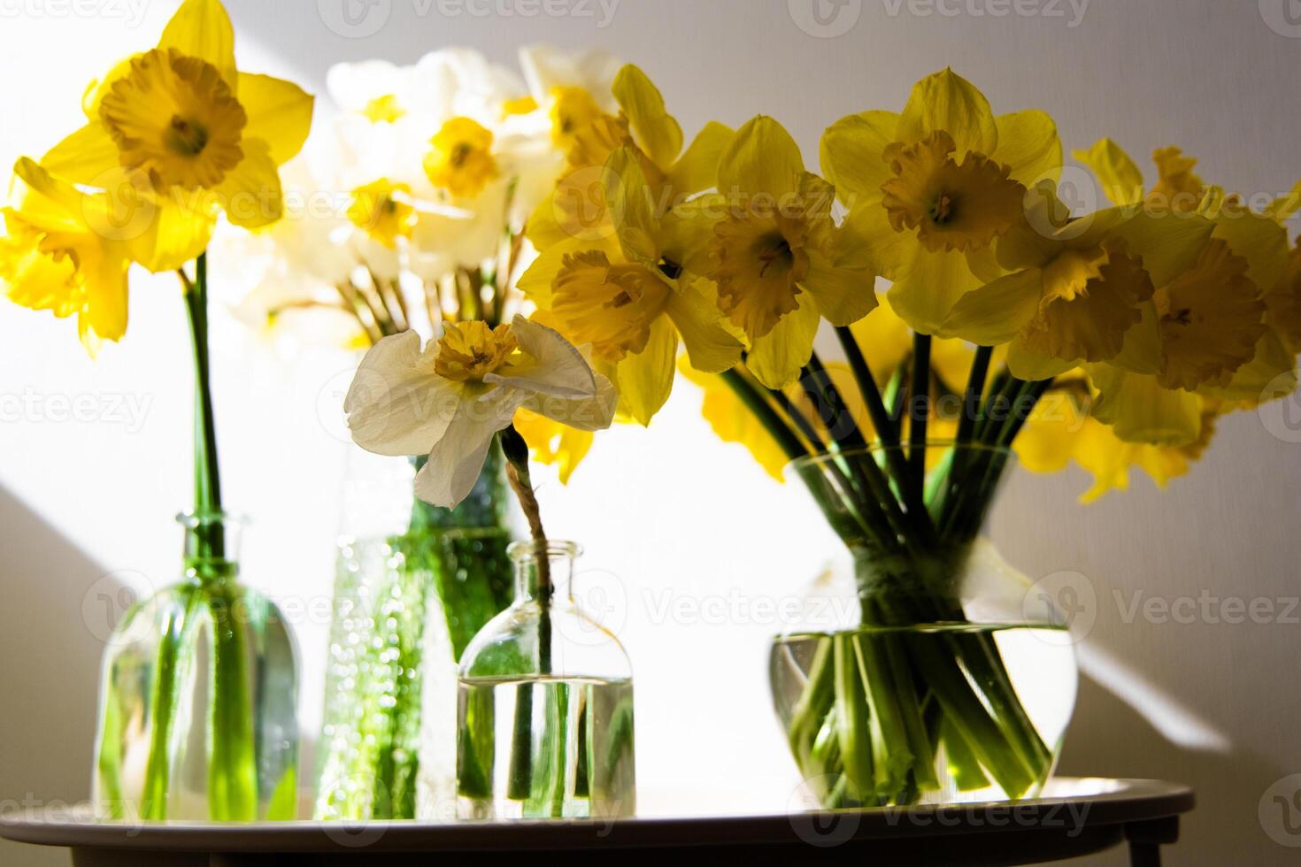 Bright yellow daffodils arranged in vases create a cheerful display on a sunlit table photo