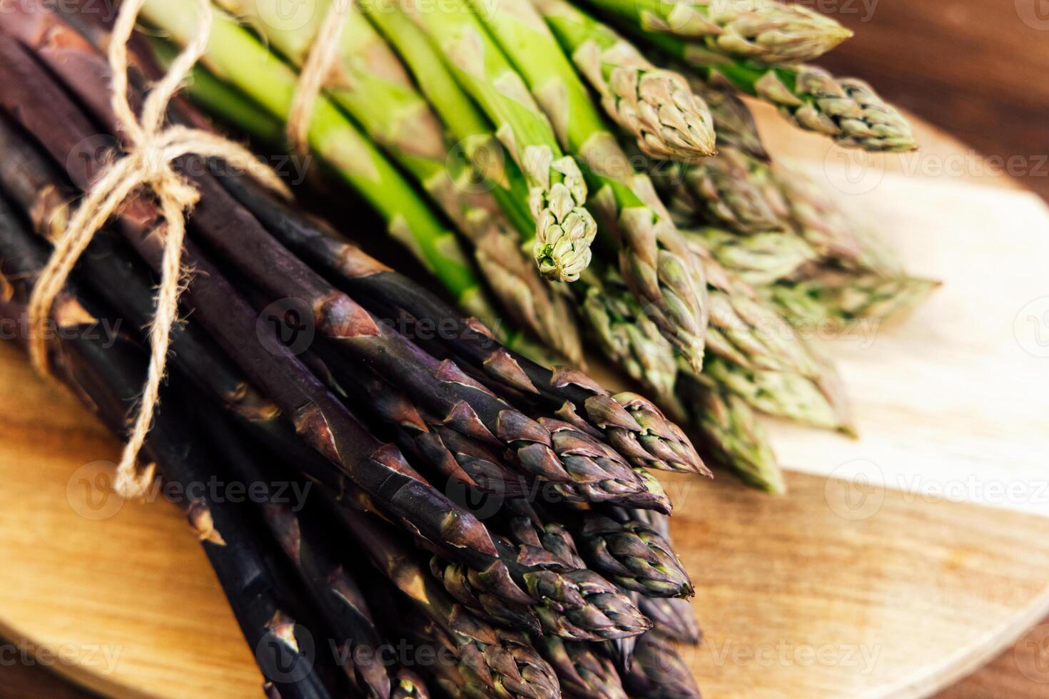 Freshly harvested asparagus varieties on a wooden cutting board in a rustic kitchen photo