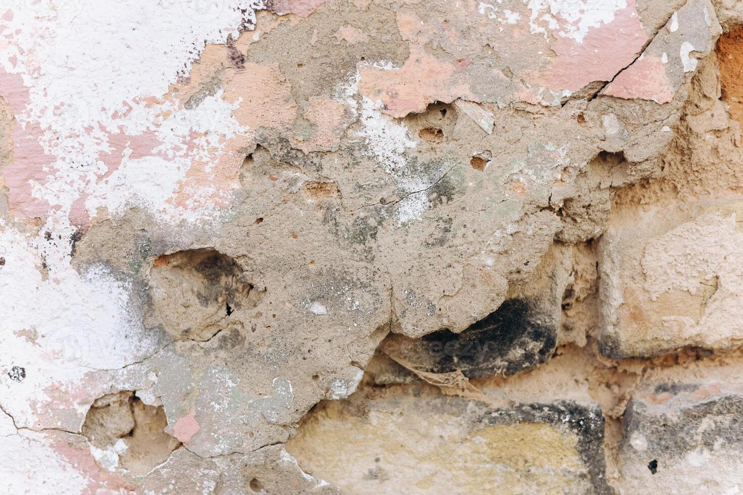 Cracked wall with peeling paint and exposed bricks in an old structure photo