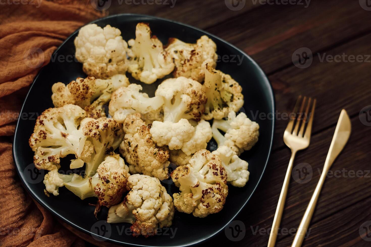 Delicious roasted cauliflower is arranged on a black plate showcasing its golden-brown texture photo