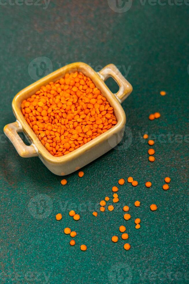 Colorful orange lentils in a small bowl on a green background photo