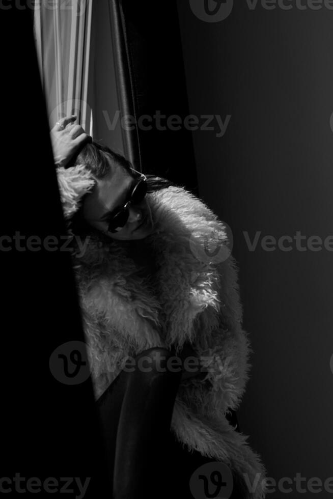 Black and white portrait of a beautiful woman in a fur coat and sunglasses photo