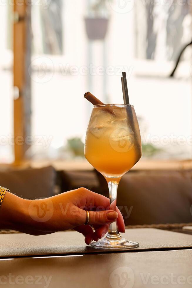 Cocktail with ice and cinnamon in a glass on the table photo