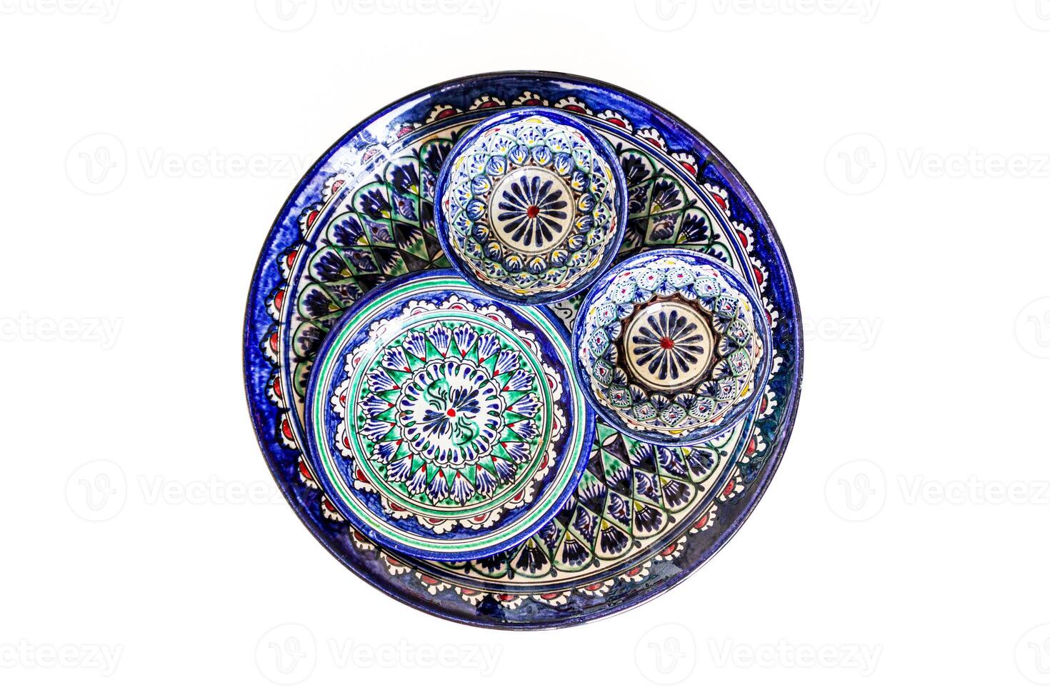 Ceramic dishes showcasing intricate oriental patterns, predominantly in blue, green, and white. The largest plate features a detailed mandala-like design with a series of floral and geometric motifs. photo