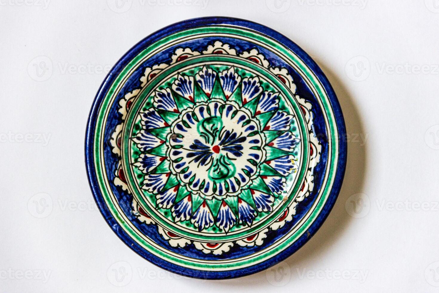 Ceramic dish with intricate patterns, typical of Uzbek pottery. Features a central floral motif surrounded by a radial arrangement. photo