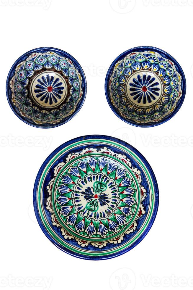 Ceramic dishes featuring intricate geometric and floral patterns. The largest dish is decorated with concentric circles and repeating motifs in blue, green, and white, accented with red and black. photo