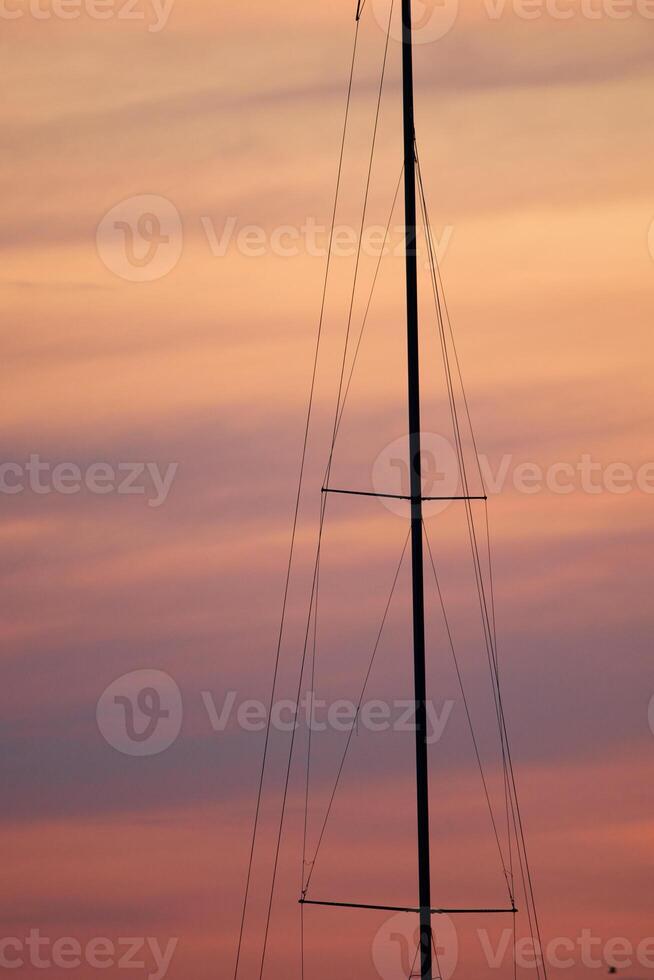 the mast of a sailing boat on the background of a pink sunset sky photo