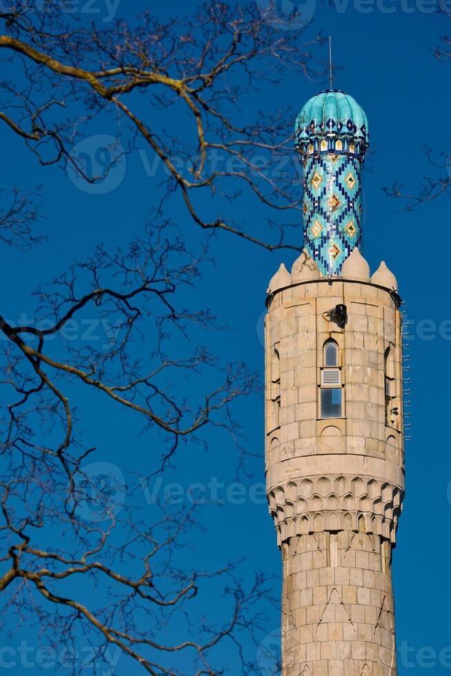 Tower of The blue dome with the golden crescent of the mosque in St.Petersburg - Russia through the branches of trees on a clear spring day photo