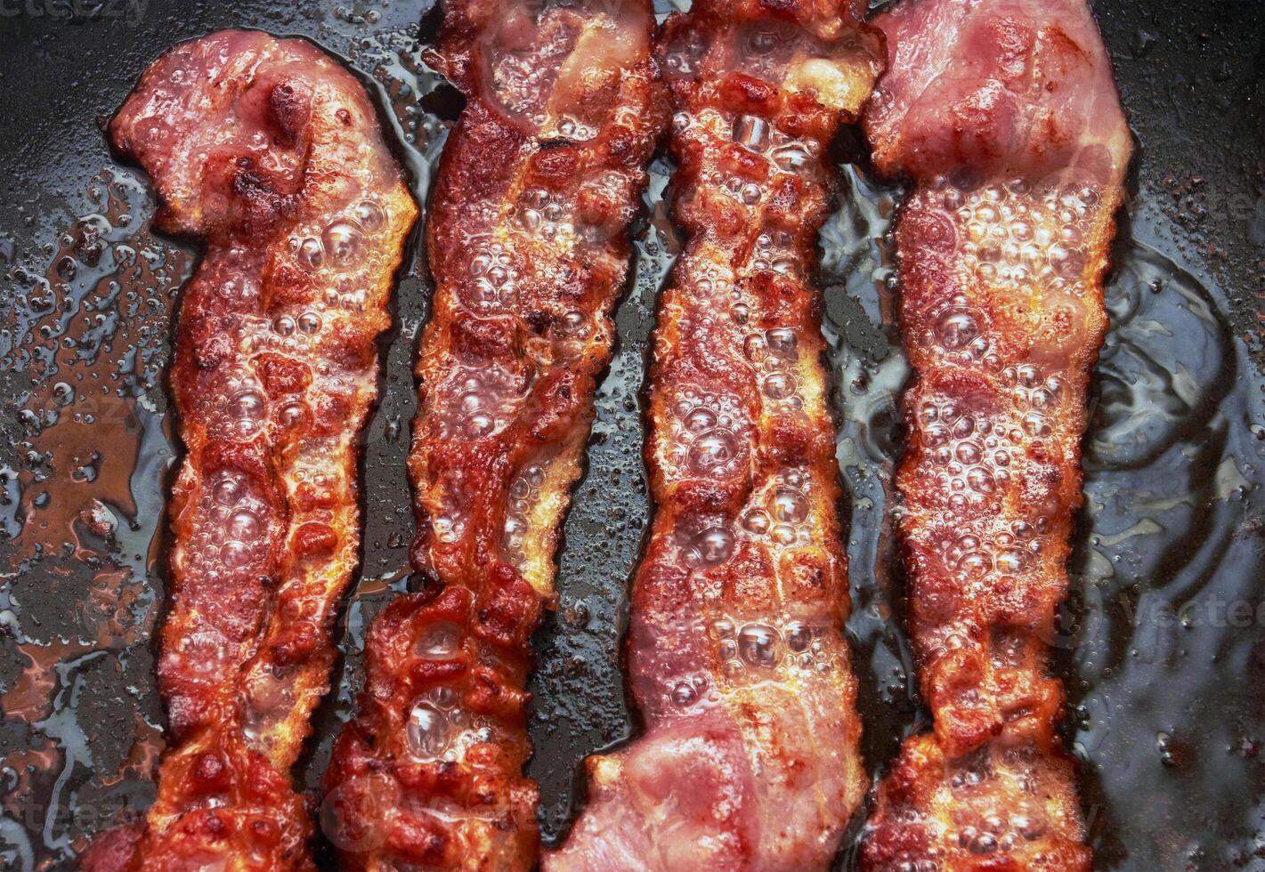 Bacon slice being cooked in frying pan photo