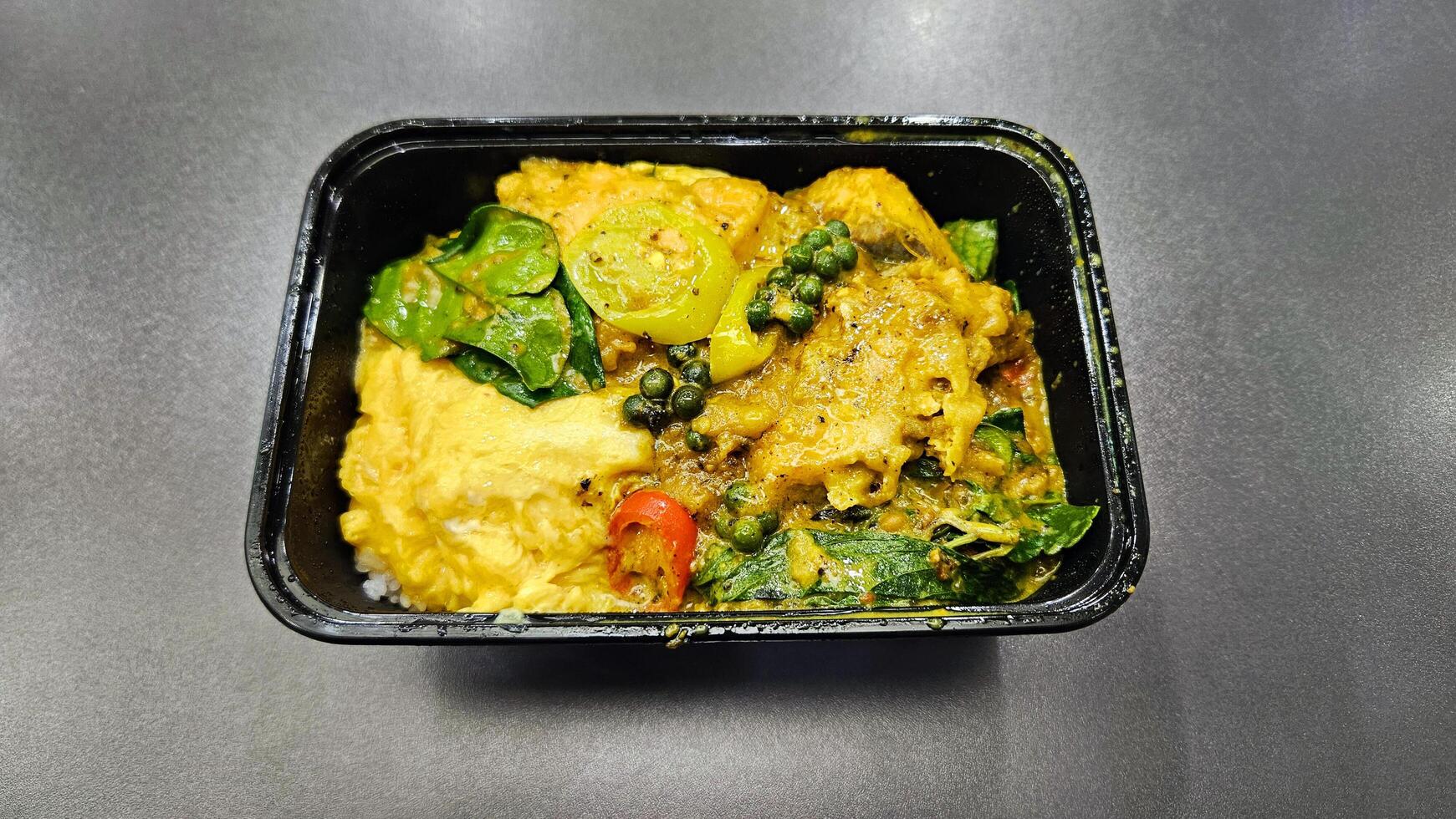 Salmon fried with southern curry paste and scrambled eggs on rice in black plastic box. photo